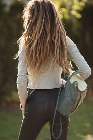 Bag on woman back, girl with dreadlocks hairstyle