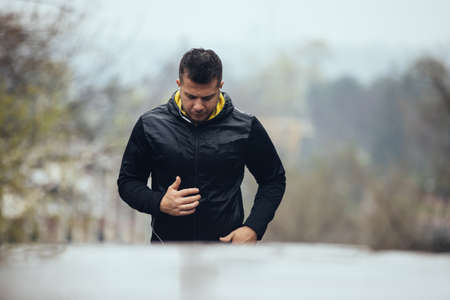 Sports man jogging outdoors in rainy day