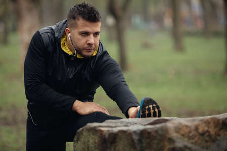 Sports man jogger warming up, stretching his legの写真素材