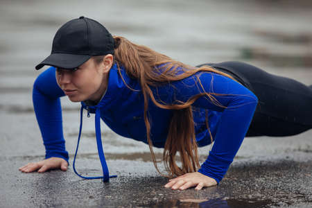 Young athletic woman push ups in the rainの写真素材