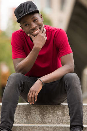 Stylish man in pink t-shirt sitting in urban city streetの写真素材