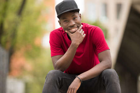 Stylish man in pink t-shirt sitting in urban city streetの写真素材