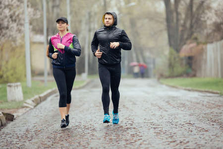 Two friends or couple jogging at the rainy day
