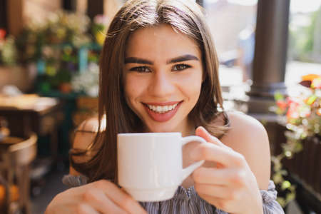 Pretty young woman drinking tea with biscuit in restaurant
