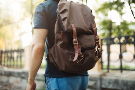 Backpack on a man, rear view of male tourist hiking travelling in park