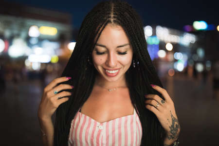 Sexy woman portrait with african pigtails in night city street