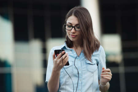 Girl using smart phone with earphones listening musicの写真素材