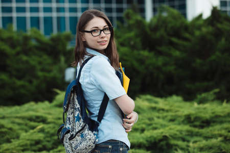 Student girl portrait outdoors near college or university holding folders ready to studyの写真素材