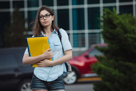 Luxury student girl portrait outdoor near university holding folders, cars on backgroundの写真素材