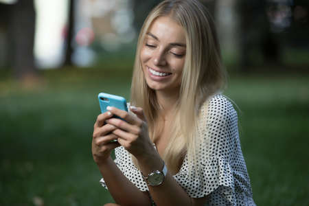 Woman using phone on grassの写真素材