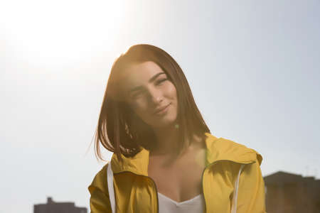 Pretty woman outdoor portrait at sky background in yellow windbreakerの写真素材