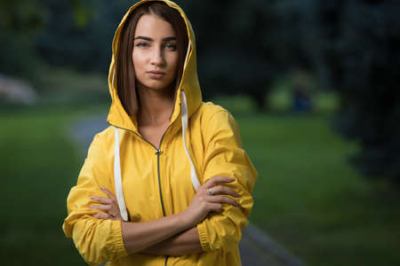 Woman wear yellow raincoat with hood in parkの写真素材