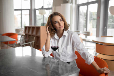 Young woman holding red wine glass sitting in the restaurantの写真素材