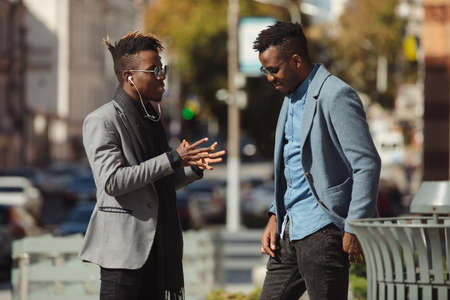 Two young african businessmen friends talking on the street