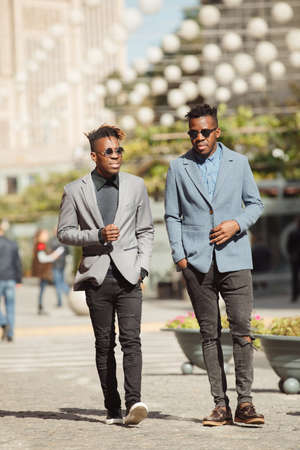 Two young african businessmen friends walking and talking on the city streetの写真素材