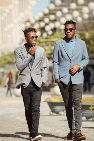 Two young african businessmen friends walking and talking on the city streetの写真素材