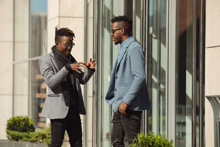 Two young african businessmen friends talking on the streetの写真素材