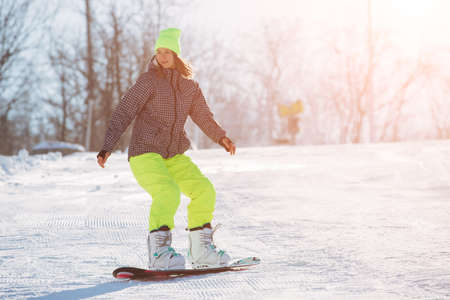 Winter sport activity, woman snowboarder riding on slopeの写真素材