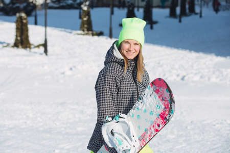 Woman carrying her snowboard on snowy slopeの写真素材