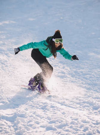 Woman snowboarder riding down from hill