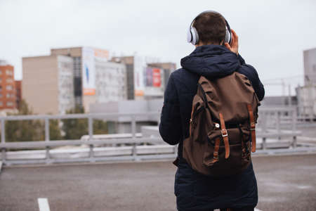 Man in headphones listening to music outdoors, back viewの写真素材