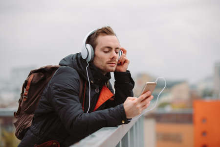 Man in headphones listening to music outdoors in city