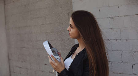 Young stylish woman holding headphones near wallの写真素材
