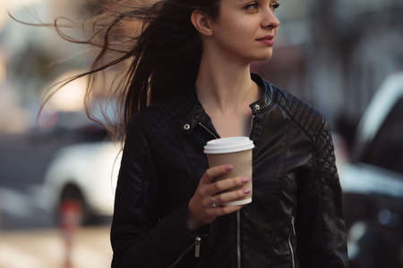 Woman enjoying to walking with coffee cup in city street