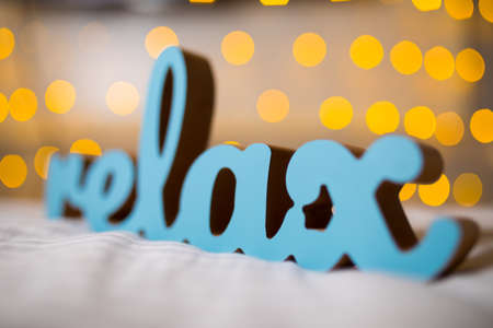 Wooden word relax on a bed with yellow blurred lights bokeh backgroundの写真素材