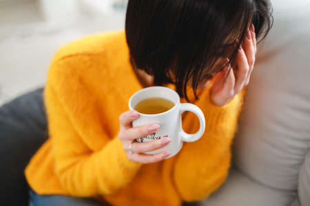 Woman drinking tea cup in apartment sitting on sova at the morning weekend rest dayの写真素材