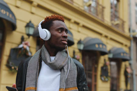 African american man listening to music in headphones at city