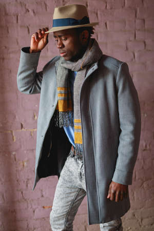 African american man portrait in coat and hat against pink wall backgroundの写真素材