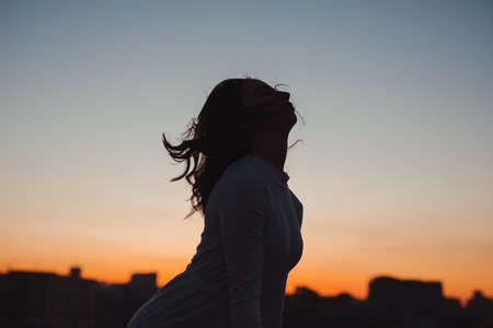 Silhouette of woman toss her hair at sunset in the cityの写真素材