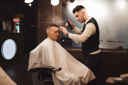 Professional barber splashes water on a client head in the barbershop salonの写真素材