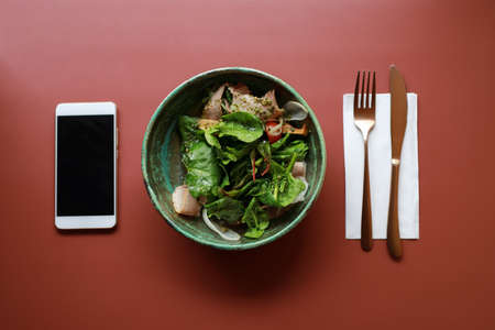 Plate with salad and empty screen of smartphone on the table, flat layの写真素材