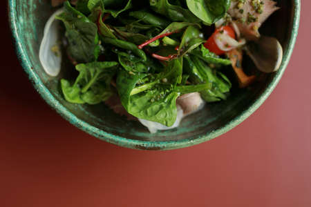 Half plate with healthy fresh salad on a coral color tableの写真素材
