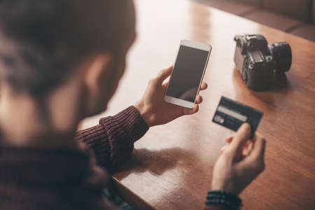 Online banking with smart phone, man photographer rewrite a number of credit cardの写真素材