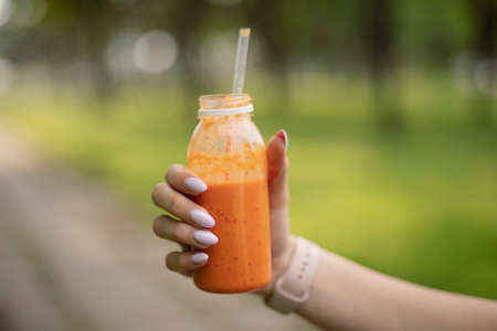 Healthy orange smoothie in a fitness woman handの写真素材
