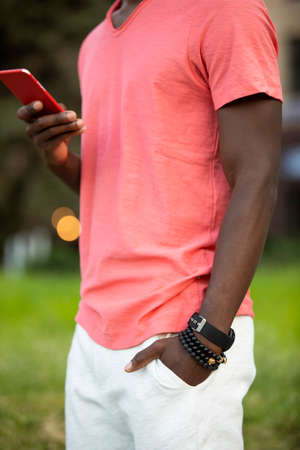 Unrecognizable African american man in living coral t-shirt using smartphone send the messageの写真素材