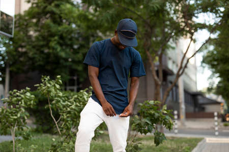 African american man in empty t-shirt and cap standing in summer city street