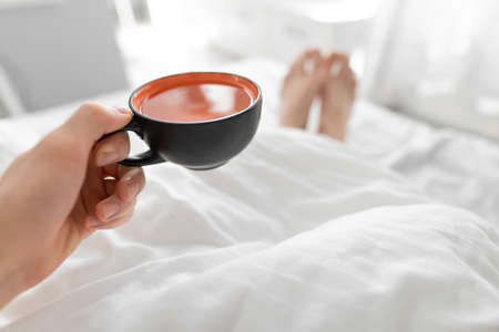 POV, man drinking morning tea in a bedの写真素材