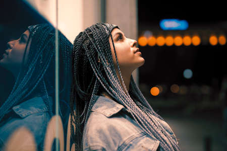 Portrait of young unusual woman leaning on building in the night cityの写真素材