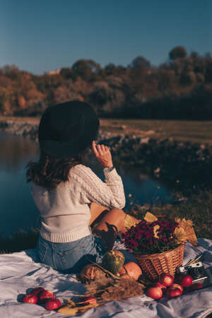 Art portrait of woman in hat on the nature sitting near lakeの写真素材