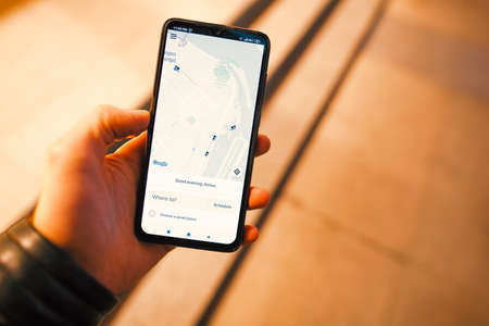 Dnipro / Ukraine, October 18, 2019: Male hand holding smartphone with Uber application at night cityのeditorial素材