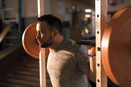 Man squat with barbell in a fitness gym making his muscles more strong