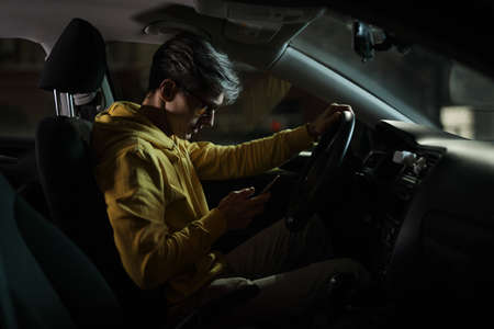 Driver man using smartphone in car phone holder at nightの写真素材