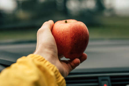 Light apple snack in the car, male hand take ripe fruitの写真素材