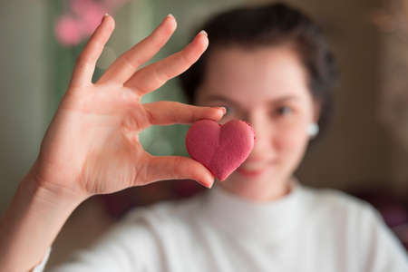 Woman holding pink macaroon in the heart shape