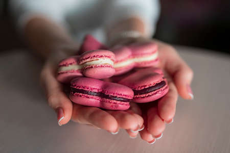 Woman hands holding many pink macaroons in the heart shapeの写真素材