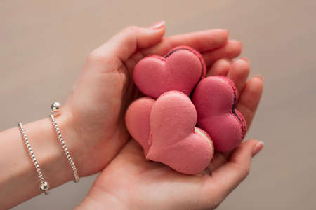 Woman hands holding many pink macaroons in the heart shapeの写真素材